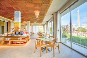 A spacious dining area with high ceilings and large windows offering a view of the cityscape.