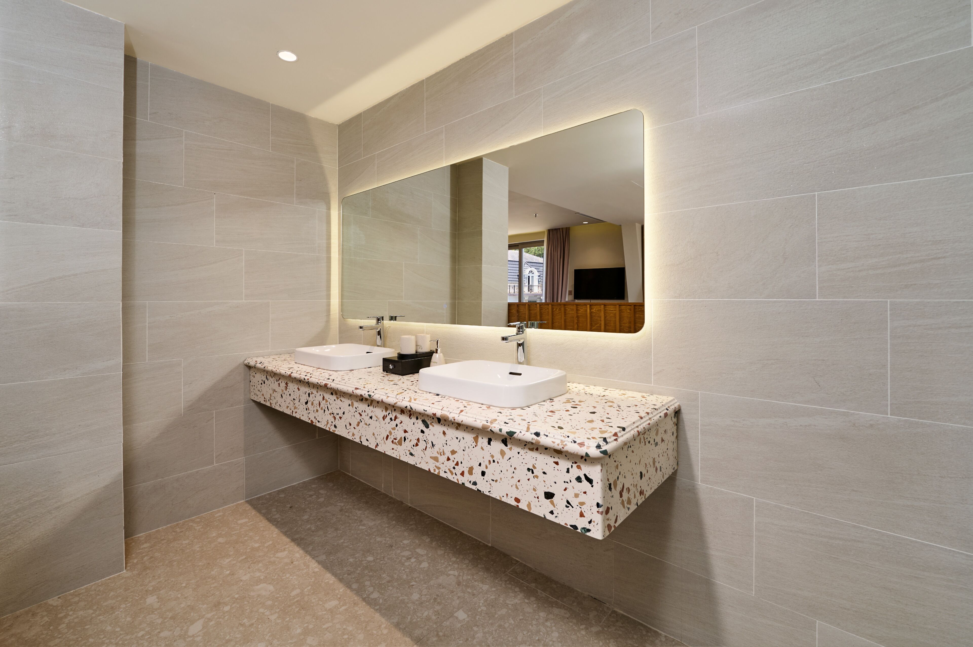 A modern bathroom with two sinks, a large mirror, and a terrazzo countertop.