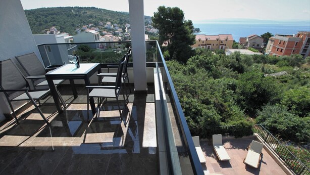 Ein Balkon mit Pool, Gartenmöbeln und Blick auf das Meer und Gebäude.