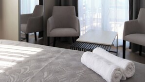 Ein Hotelzimmer mit einem Bett, zwei Sesseln, einem kleinen Tisch und einem großen Spiegel.