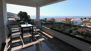 Ein Balkon mit Tisch und Stühlen, freie Sicht auf das Meer und Gebäude.