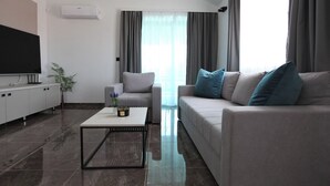 Ein modernes Wohnzimmer mit Flachbildfernseher, grauem Sofa und Couchtisch.