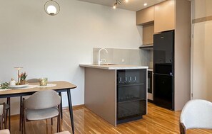 A compact kitchen with a sink, a refrigerator, and a dining area with chairs and a table. - Nice apartment in Krvavac II with WiFi (Krvavac II)