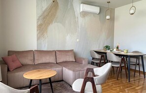 A modern living room with a sectional sofa, a round wooden coffee table, and a dining area with a table and chairs. - Nice apartment in Krvavac II with WiFi (Krvavac II)