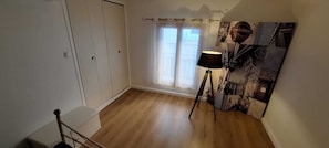 Ett rum med trägolv, en trappa, ett fönster med gardiner och en lampa.