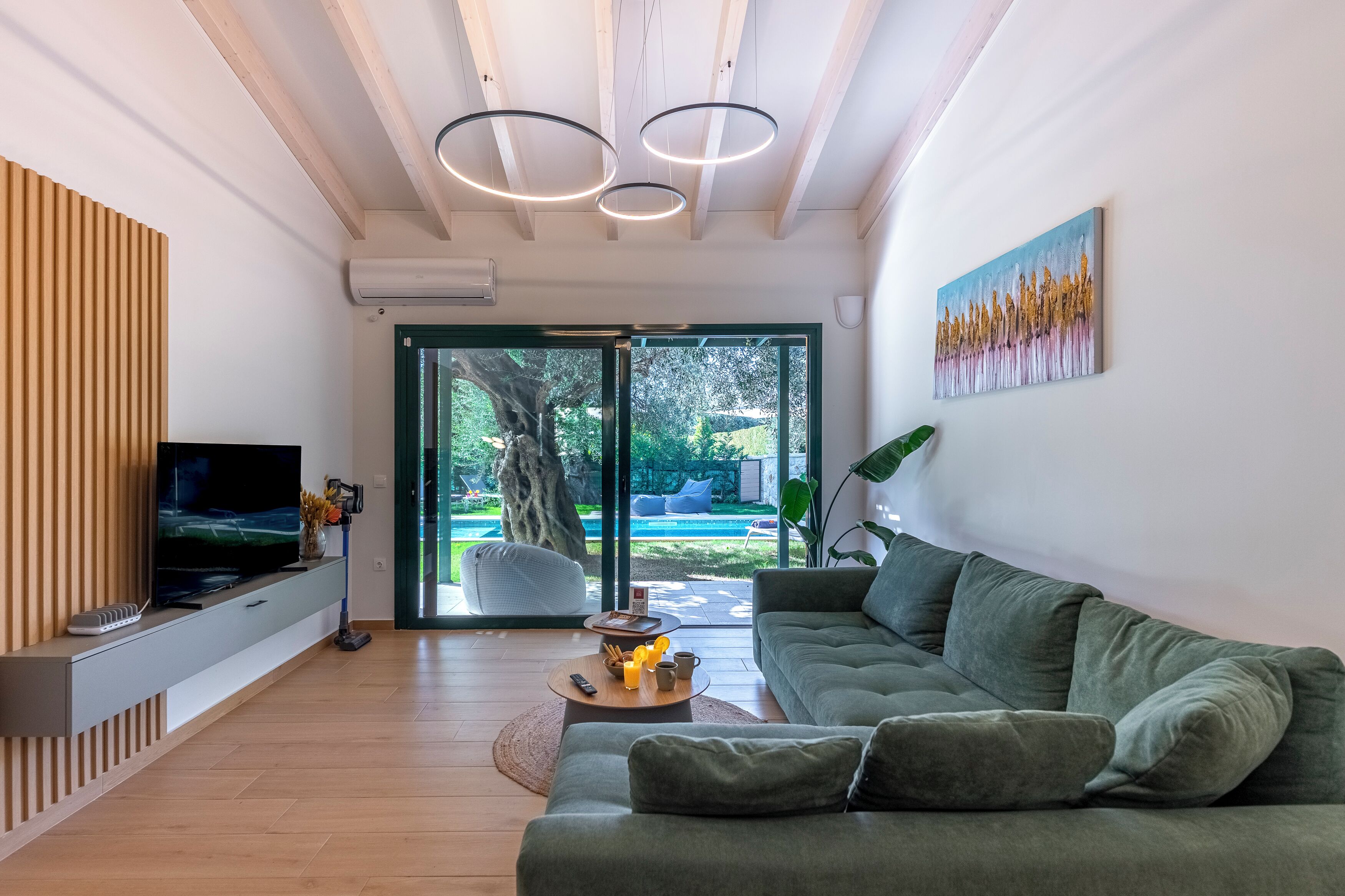 Uma sala de estar moderna com uma TV de tela plana, um sofá verde, uma mesa de centro e uma pintura na parede.