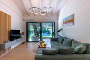 Una sala de estar moderna con un televisor de pantalla plana, un sofá verde, una mesa de centro y un cuadro en la pared.