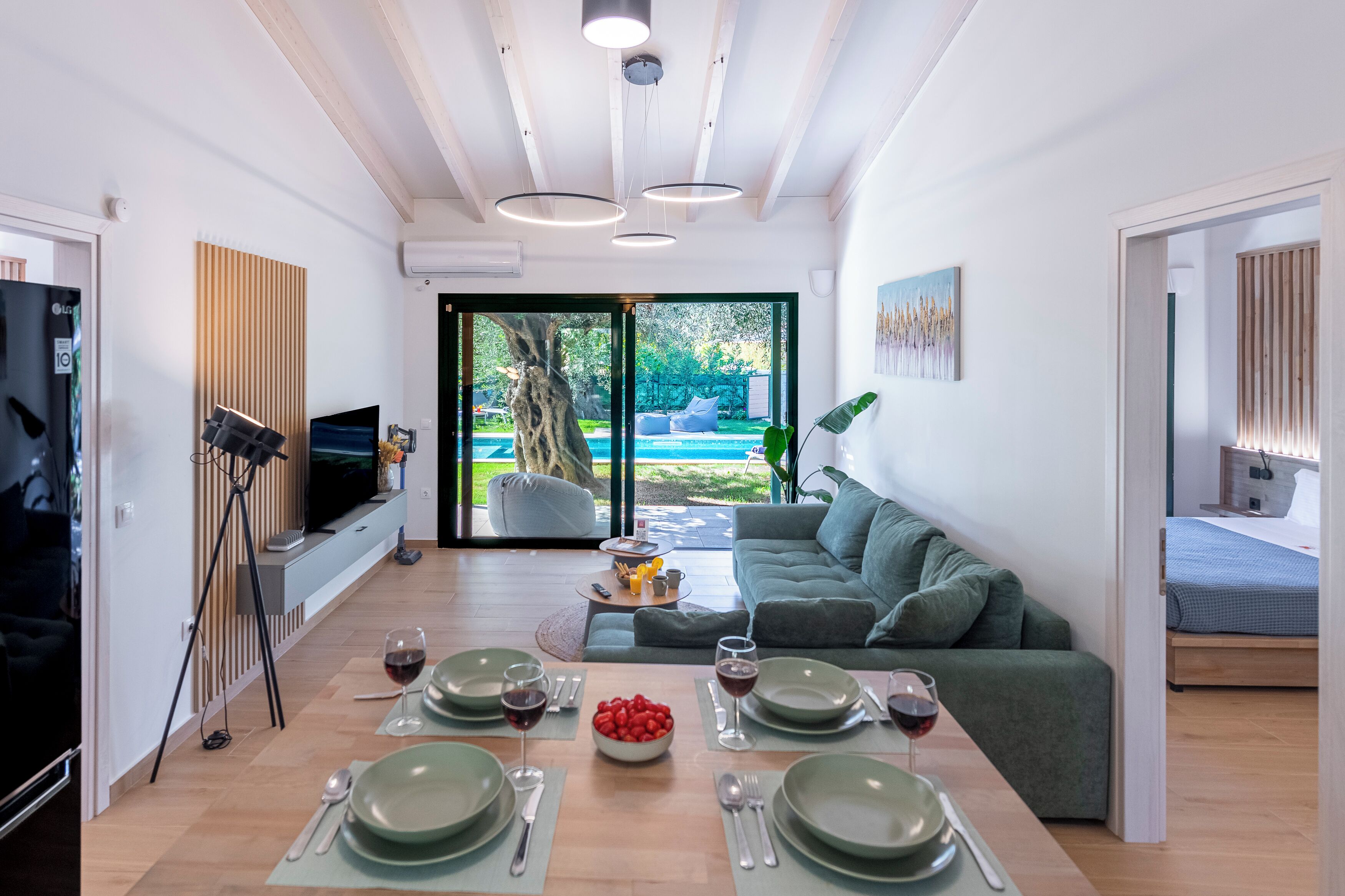 Sala de estar moderna com área de jantar, sofá, TV e vista para o exterior.
