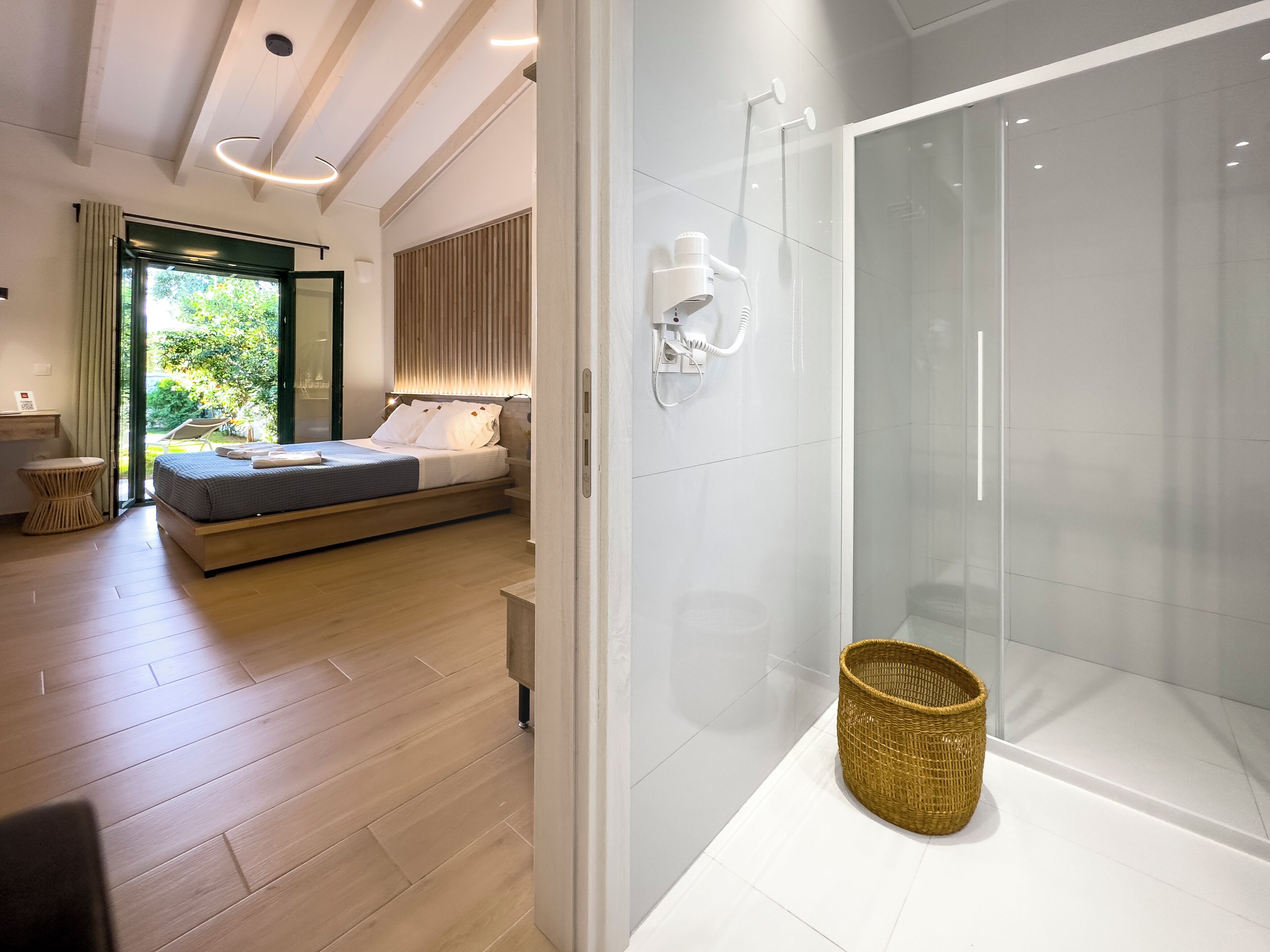 A modern bedroom with a bed, bedside table, and a glass shower enclosure.