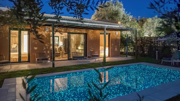 Et moderne hus med swimmingpool, glasdøre og en patio.