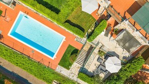 Eine Vogelperspektive auf einen Poolbereich mit einer Steintreppe, die zu einer überdachten Sitzgelegenheit führt.