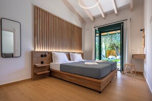 Ein modernes Schlafzimmer mit einem Holzkopfende, einem großen Bett, einem Nachttisch und Blick ins Freie.
