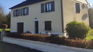 Une maison à deux étages avec un toit en pente, une porte d’entrée et une antenne parabolique.