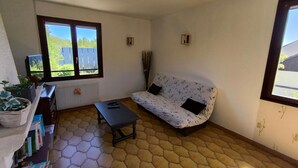 Une pièce comprenant un canapé, une table, un radiateur, une fenêtre et une bibliothèque.