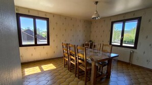 Un espace repas comprenant une table et des chaises, de grandes fenêtres offrant une vue dégagée et un sol à motifs.