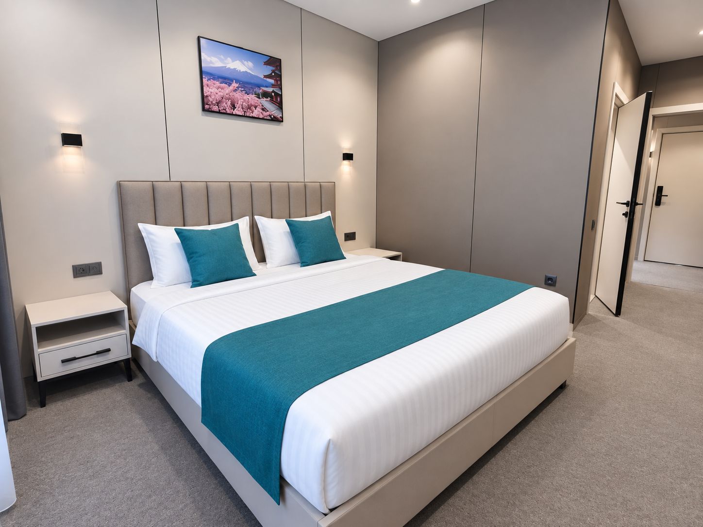 Una habitación de hotel moderna con una cama grande, una mesita de noche, un televisor de pared y una puerta.