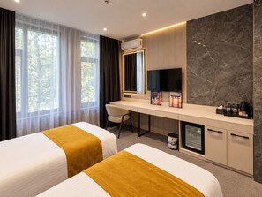 Habitación de hotel con dos camas, un escritorio, una televisión y un minibar.