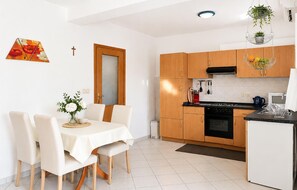Eine moderne Küche mit Holdekor, einem Esstisch mit Stühlen, einem kleinen Kühlschrank und hängenden Pflanzen.