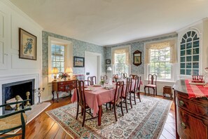 A dining room with a fireplace, a table set for six, and a large window with a view of greenery. - Private, Exclusive, Historic Pocomoke River Estate (Pocomoke City)