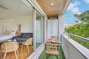 Ein Balkon mit Esstisch, Stühlen und einer Couch.
