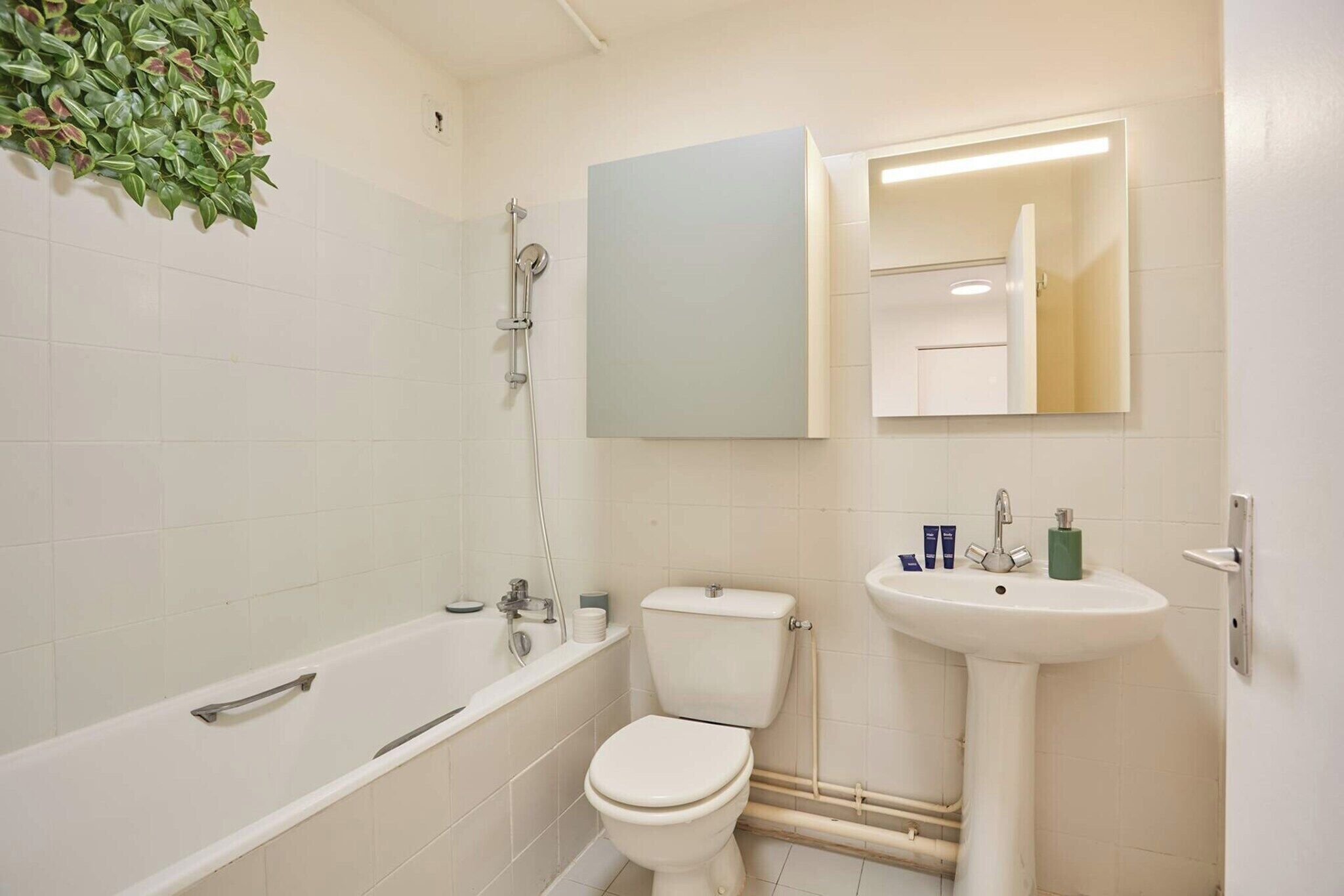 Ein Badezimmer mit Badewanne, Toilette, Waschbecken und Spiegel.