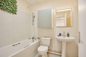 Ein Badezimmer mit Badewanne, Toilette, Waschbecken und Spiegel.