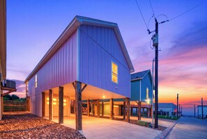 A two-story house with a covered porch, a garage, and a driveway. - Bay Views + Sunset Deck | Pool Access | Padre Island, TX | Laguna Sunset (Corpus Christi)