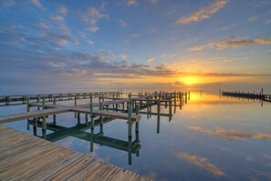 A wooden pier extending into calm water, reflecting the sky and sunset. - Bay Views + Sunset Deck | Pool Access | Padre Island, TX | Laguna Sunset (Corpus Christi)