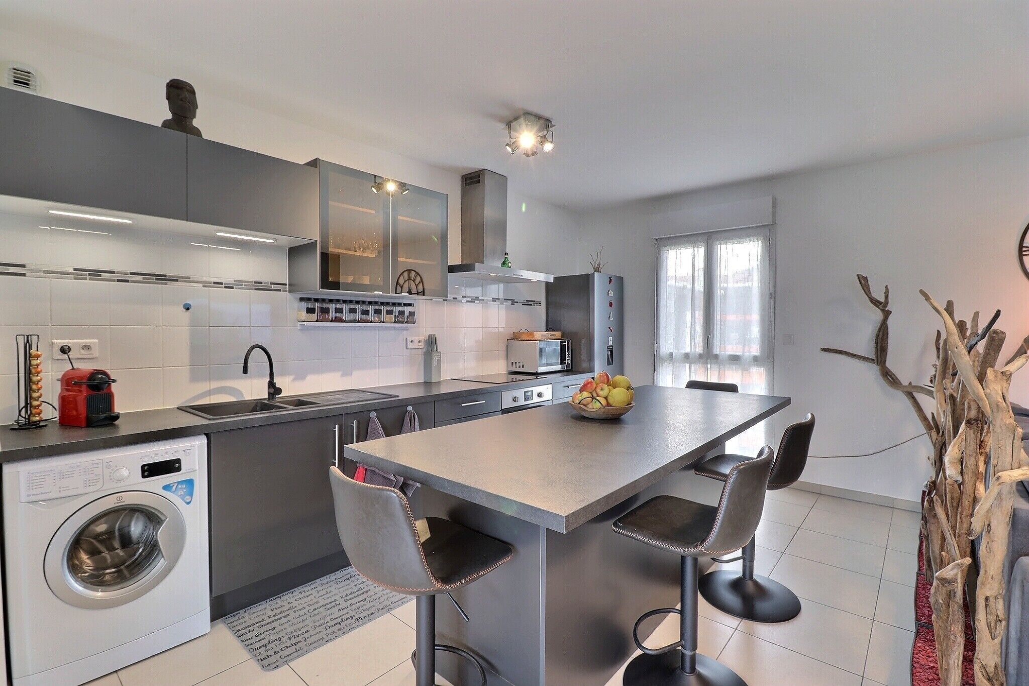 A modern kitchen with a central island, built-in appliances, and a dining area with bar stools.