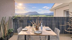 Un espace de restauration en plein air avec une table dressée pour quatre personnes, entourée de chaises, et offrant une vue sur un paysage montagneux.