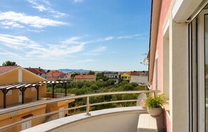 A balcony with a metal railing, a potted plant, and a view of a residential area with houses and mountains in the distance. - Nice apartment in Sukosan with WiFi (Sukosan)