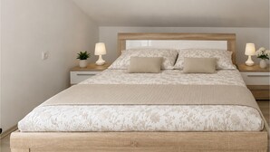 Une chambre à coucher avec un lit, deux tables de chevet, deux lampes et une plante en pot.