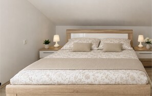 A bedroom with a bed, two bedside tables, two lamps, and a potted plant. - Nice apartment in Sukosan with WiFi (Sukosan)
