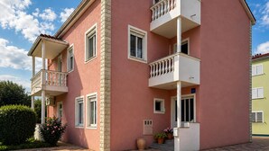 Un bâtiment rose doté de balcons, de fenêtres et d’une petite porte.