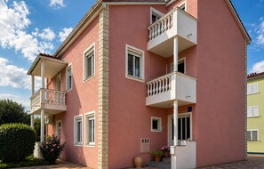 A pink building with balconies, windows, and a small door. - Nice apartment in Sukosan with WiFi (Sukosan)