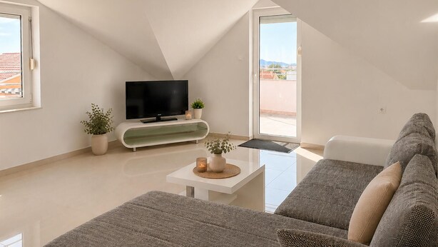 Un salon moderne avec un téléviseur à écran plat, un canapé, une table basse et une plante en pot.