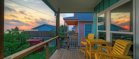 A wooden deck with outdoor furniture, a covered area, and a view of houses and sky.