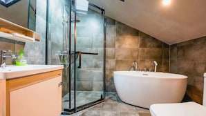 Ein modernes Badezimmer mit einer Duschkabine, einer freistehenden Badewanne und einem Waschtisch mit Spiegel.