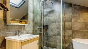 Ein modernes Badezimmer mit Duschkabine aus Glas, einem Waschbecken mit Holzschrank und einer großen Badewanne.