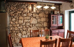 A stone wall, wooden chairs, a table with a patterned tablecloth, a cabinet, and a clock on the wall. - 2 bedroom gorgeous home in Grizane-Belgrad (Grizane-Belgrad)