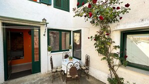 Eine Terrasse im Freien mit Tisch und Stühlen, einem Blumentopf und einer Kletterrose.