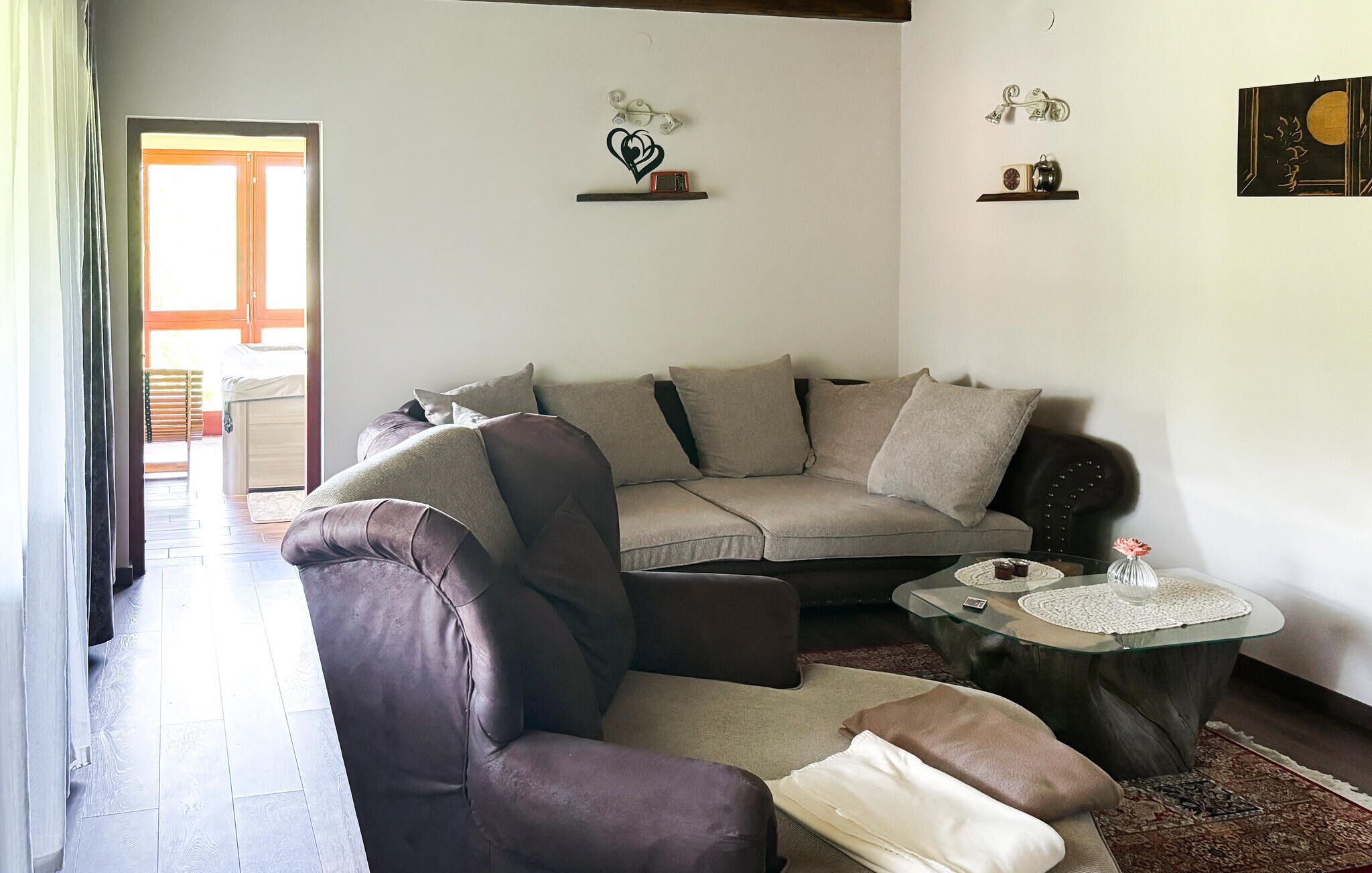 Ein Wohnzimmer mit Sofa, Sessel und Couchtisch, einer Tür zum Außenbereich und Wanddekorationen.