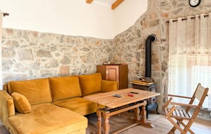 Ein gemütliches Zimmer mit Steinwand, Holztisch, Sofa und Sessel.