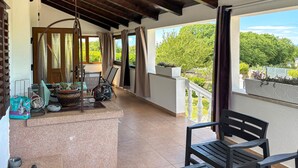 Een balkon met uitzicht op groen, een stoel, een tafel en een hangstoel.