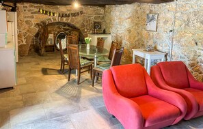 A stone-walled room with a dining table, chairs, and a red sofa. - Stunning home in Dobrinj (Dobrinj)