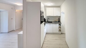 Een moderne keuken met witte kastjes, een ingebouwde oven en een spoelbak.