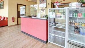 A reception area with a red counter, a glass display case with beverages, and a clock on the wall. - Stylish DBL Suite Escape W/ Free Wifi and Parking (Batam)
