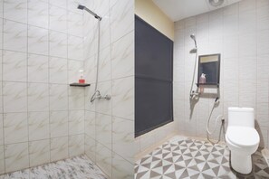 A bathroom with a shower, toilet, and a small shelf with a bottle. - Stylish DBL Suite Escape W/ Free Wifi and Parking (Batam)