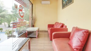 A room with a glass partition, red leather sofas, a small table, and a potted plant. - Stylish DBL Suite Escape W/ Free Wifi and Parking (Batam)