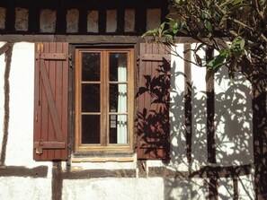 Ein rustikales Gebäude mit Holztür, Fensterläden und einem kleinen Fenster.